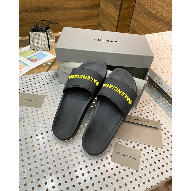 Ba*len*cia*ga pool slide sandal in black rubber with yellow 3d Ba*len*cia*ga logo